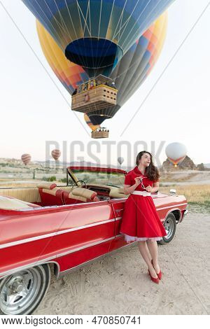 Beautiful Girl In Retro Style Posing Near A Vintage Red Cabriolet Car On Background Of Balloons In C