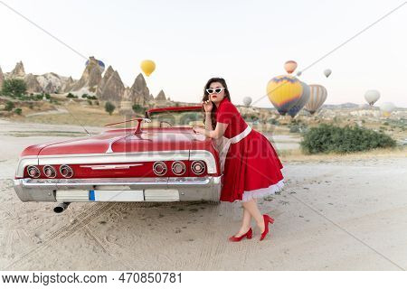 Beautiful Girl In Retro Style Posing Near A Vintage Red Cabriolet Car On Background Of Balloons In C