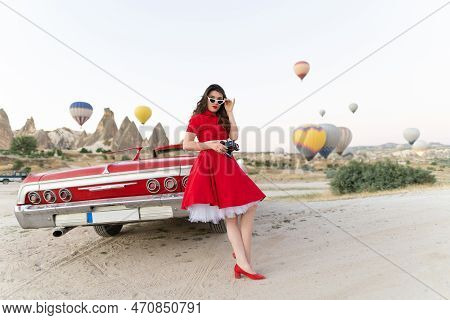 Beautiful Girl Retro Style Posing Near Vintage Red Cabriolet Car With Old Film Camera  On Background