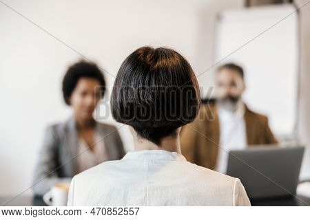 Rear View Of A Young Woman Sitting At The Office With Managers At The Job Interview.