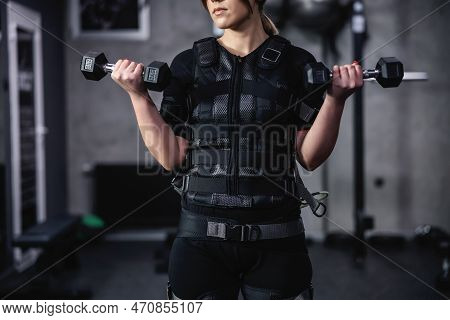 Front Portrait Of A Part Woman's Body In A Black Ems Training Suit. She Holds Dumbbells In Her Hands