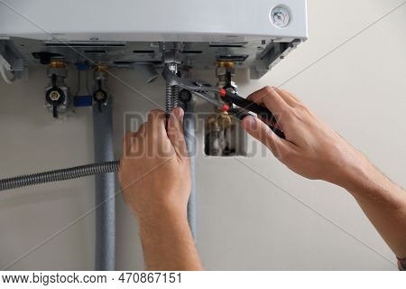 Man Repairing Gas Boiler With Waterpump Plier, Closeup