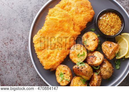 Munich Schnitzel Served With Baked Potatoes And Mustard Close-up In A Plate On The Table. Horizontal