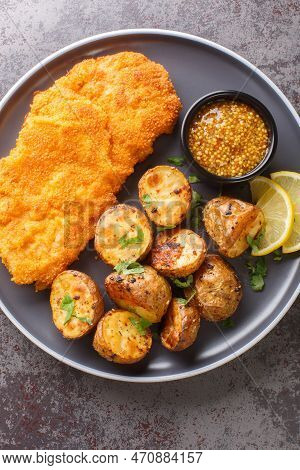 Munchner Schnitzel With Baked Potatoes And Dijon Mustard Closeup On The Plate On The Table. Vertical