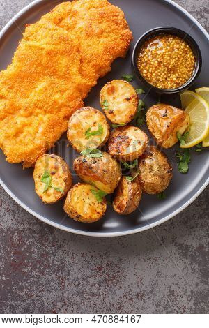 Fried Veal Schnitzel With Lemon And Garnish Of Baked Potatoes Close-up In A Plate On The Table. Vert