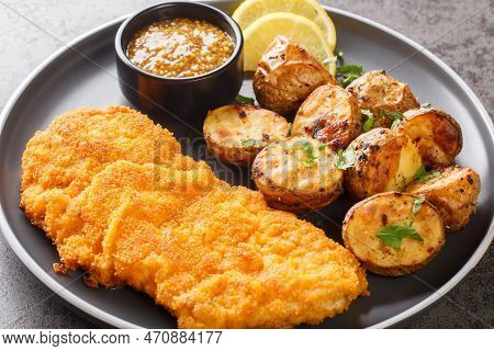 Munich Schnitzel Served With Baked Potatoes And Mustard Close-up In A Plate On The Table. Horizontal