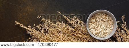 Oat Flakes In A Bowl And Ears Of Oats On A Brown Background, Top View