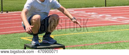 A Male High School Teenager Landing On A Ploys Box In A Squat Position On A Turf Field At Summer Spo