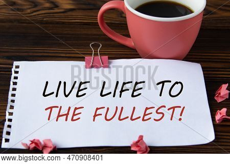 Live Life To The Fullest! - Words On A White Sheet On A Wooden Brown Background With A Cup Of Coffee