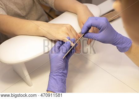 Manicure Mater Files Beautiful Womans Nails, Holding Finger. Caucasian Manicure Master Works In Glov