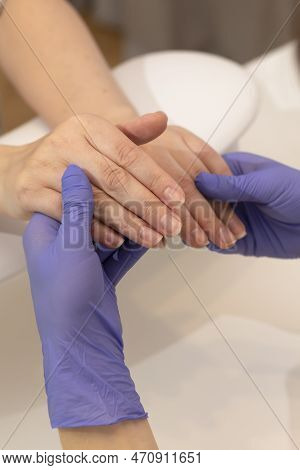 White Manicure Technician, Nail Stylist In Gloves Holds Hands Of Caucasian Client, Preparing Japanes