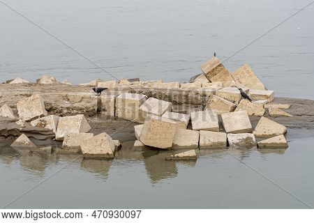 Concrete Block And Caron Black Crow. Gray Cement Cinder Block Isolated On River Side. Granite Bolder