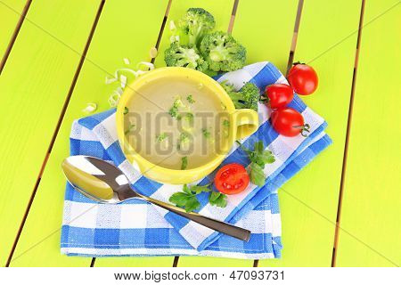 Dietní polévka se zeleninou v poháru na zelený dřevěný stůl detail