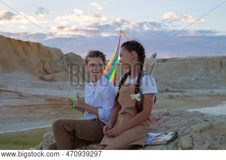 A Boy And A Girl 8-9 Years Old With Kite Are Having Fun Talking On Mountain.