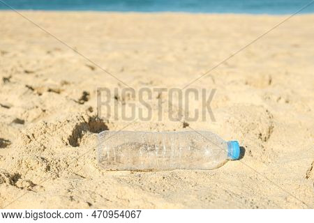 Empty Plastic Bottle From Drinking Water Lying On The Sandy Beach. The Problem Of Ocean Plastic Poll