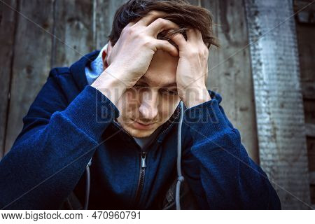 Sad Young Man On The Old Wooden Wall Background Outdoor