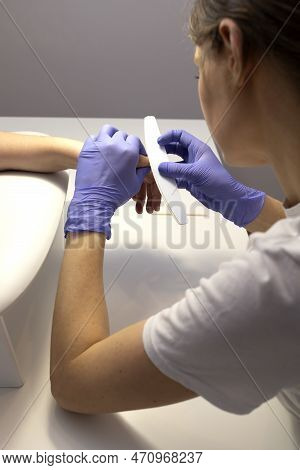 Manicurist Polishes Cuticle, Fingers Skin, Surface With File. Caucasian Manicure Master Works In Glo