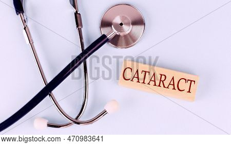 On A Blue Background, Stethoscope And Wooden Block With The Word Cataract .medical Concept