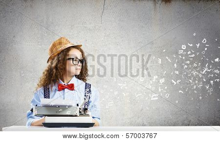 Young funny woman in glasses using typewriter