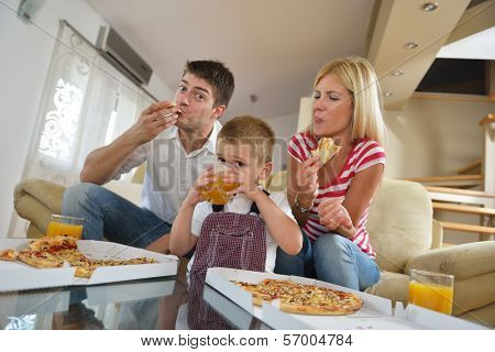 happy young family eating tasty pizza with cheesa and dring healthy and fresh orange juice