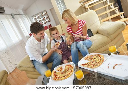 happy young family eating tasty pizza with cheesa and dring healthy and fresh orange juice