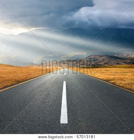 Driving On Asphalt Road At Sunset Towards The Sunbeams