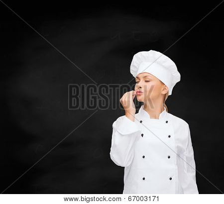 cooking, gesture and food concept - smiling female chef showing delicious gesture