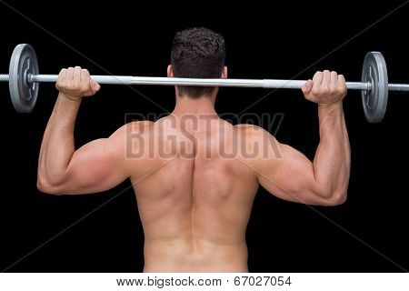 Serious crossfitter lifting up barbell behind head on black background