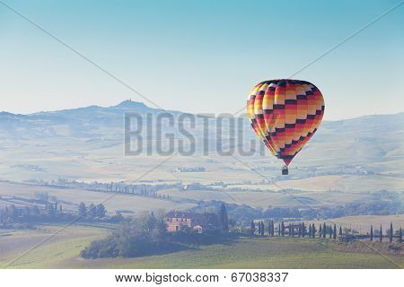 big balloon flies over rural houses Tuscany