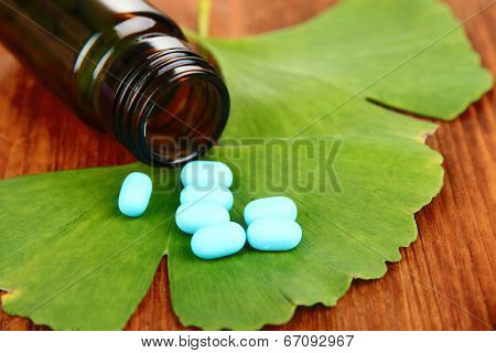 Ginkgo biloba leaves and medicine bottle on wooden background