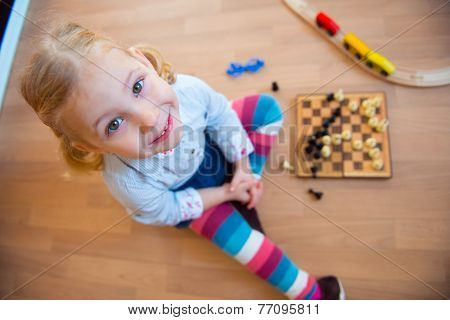 Cute Little Girl Sitting On Floor And Playing