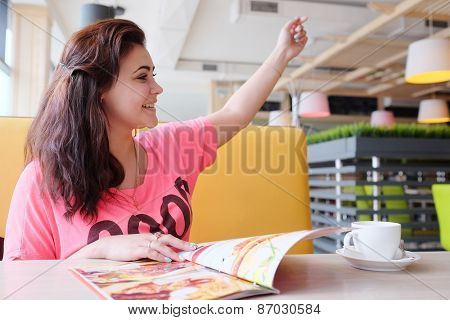Young woman calls up the waiter in the restaurant