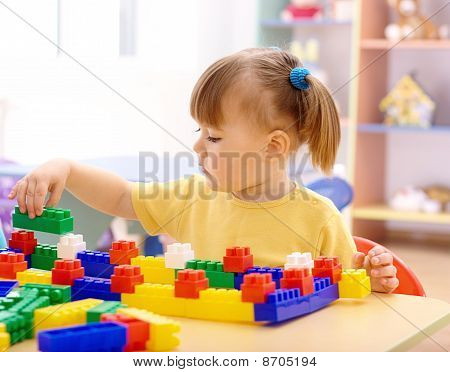 Malá holčička hrát s stavební cihly v mateřské školce