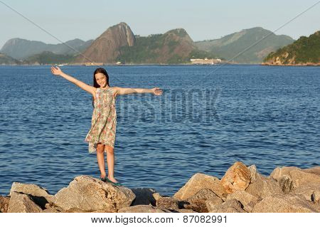 Happy Smiling Beautiful Teen Girl Standing On Stones With Long Brown Hairs Near Sea