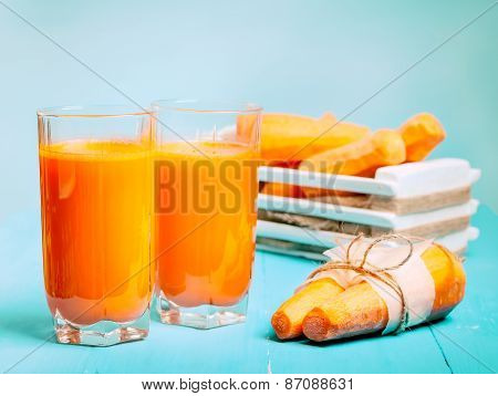 Freshly squeezed carrot juice in the glasses.A box with purified carrot on a blue wooden background.