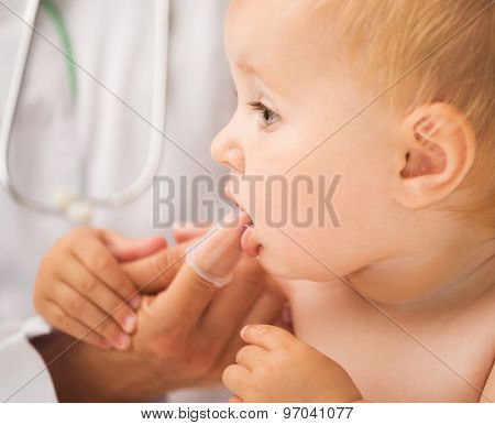 doctor cleaning baby`s mouth with special fingertip brush for children