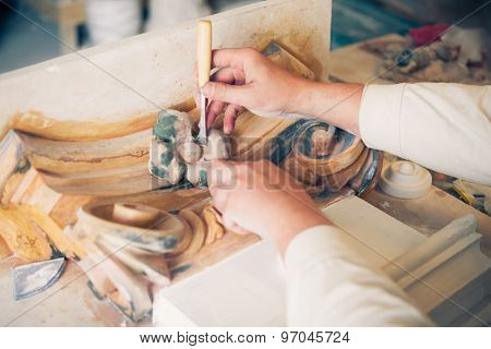 hands of restorer working with antique decor element