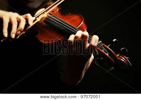 Violinist playing violin on dark background