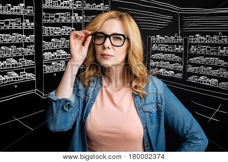Be attentive with it. Professioanl concentrated female pharmacist holdign her glasses and working in the drug store