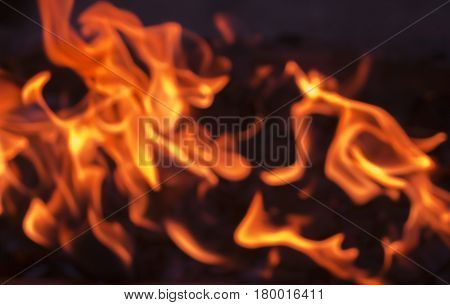Orange fire on lack coal. Abstract blurry photo for background. Blurred fireplace wallpaper. Hot burning fire banner template. Home safety and anti-fire prevention.
