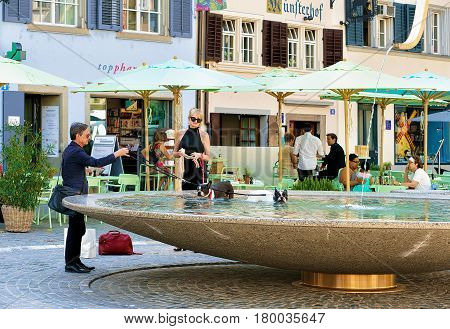 People Bathing Dogs In Fountain At Munsterhof Square In Zurich