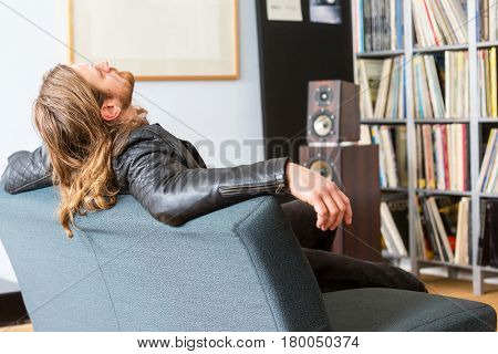 An audiophile leaning back on a couch listening to music
