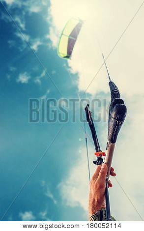 Close up image kitesurfer's hand with kite in blue sky