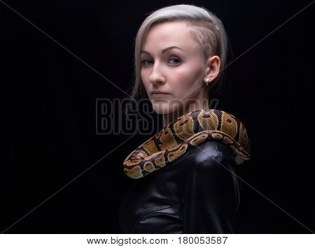 Woman in leather dress with royal python on black background