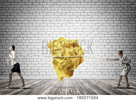 Two businesswomen playing tag of war game