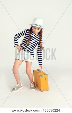 Young nice girl is trying to take a suitcase and listening to music through earphones on mobile phone. Travel, tourism, trip, voyage concept