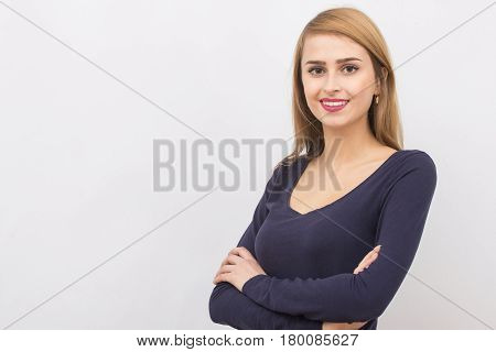 Girl posing with her hands crossed on a light gray background in the studio