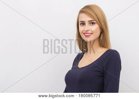 Fashion portrait of a girl posing in bright, spacious studio with a gray background in a stylish comfortable and simple clothes. young girl with clean skin and perfect face
