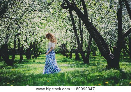 beautiful young woman in floral maxi skirt walking in spring