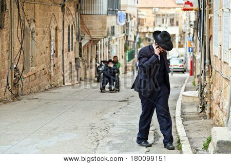 JERUSALEM, ISRAEL - DECEMBER 29, 2016: Orthodox Jewish man with mobile phone walk at street at jewish quarter in Jerusalem. 